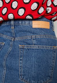 Jeans-shorts i en ljusblå nyans, med orange sömmar, en läderetikett med texten "InWear" och en klassisk femfickdesign.