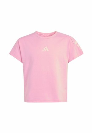 Fille marchant avec un sac à dos noir, portant un t-shirt rose, des leggings noirs avec un logo et des baskets noires avec des bandes blanches.