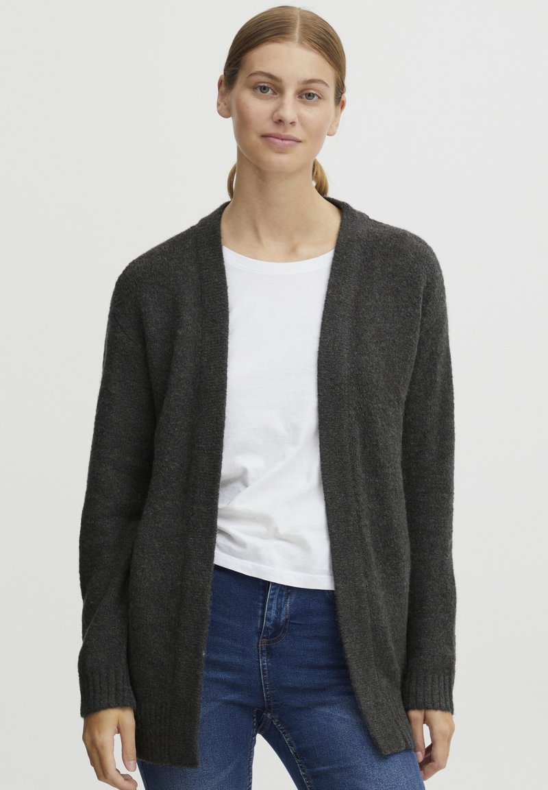 Mörkgrå öppen cardigan tillverkad av ett mjukt stickat tyg, med långa ärmar och ribbade cuffs, lagd över en vit t-shirt.