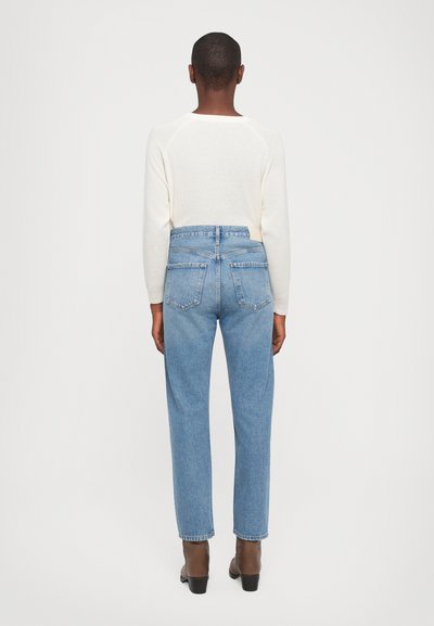 Light cream sweater with raglan sleeves paired with high-waisted, light blue denim jeans. Jeans feature two back pockets and a straight leg design.