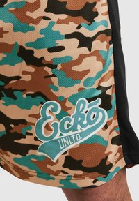 Shorts med camo-mønster i brunt, beige og teal. Har en hvit logo som sier "Eckó UNLTD." på den nederste fronten. Laget av strukturert stoff.