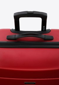 Roter Hartschalenkoffer mit strukturiertem Finish, schwarzem ausziehbarem Griff und Reißverschluss. Verfügt über eine Logoplatte an der unteren Vorderseite.