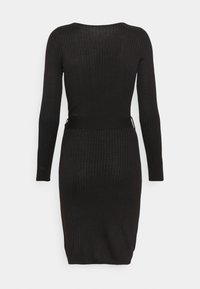 Robe noire côtelée à manches longues, coupe ajustée et encolure ronde. Texture semblable à un pull avec un détail de taille cintrée.