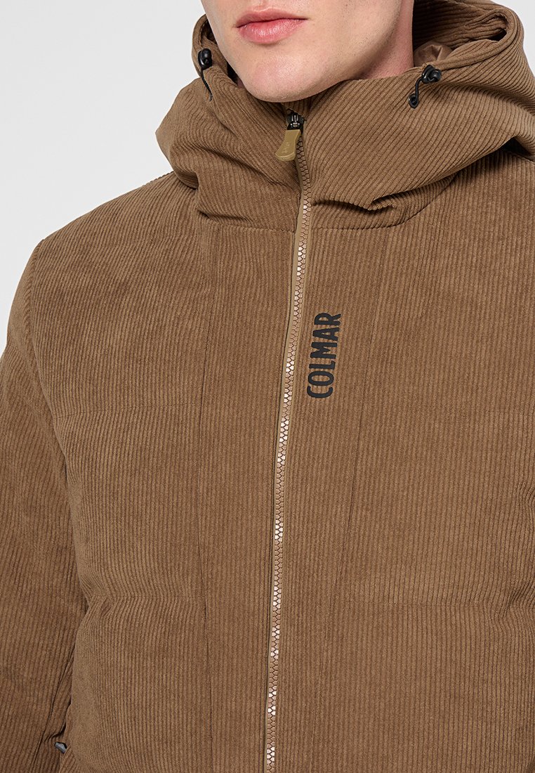 Braune Corduroy-Pufferjacke mit einem Frontreißverschluss, verstellbarem Kapuzenzug und dem auf der Brust aufgedruckten Markennamen "COLMAR". Auffällige gerippte Textur.