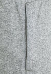 Grå bomullstyg med en mjuk textur, med en sömdetalj och en öppen ficka på sidan, med ett enhetligt vävmönster.