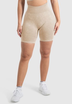 Beige hochtaillierte Shorts aus einem glatten, strukturierten Stoff mit dezenten Linien. Kombiniert mit weißen Sneakern mit schwarzen Akzenten.