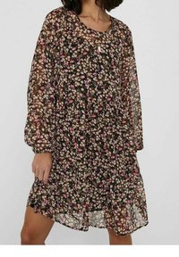 Robe fleurie à manches longues, en tissu noir transparent orné de petites fleurs roses, blanches et jaunes partout.