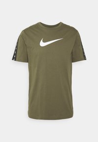 Olivově zelené tričko Nike, krátké rukávy, s velkým bílým logem swoosh na přední straně a černými bočními pruhy s bílým potiskem.