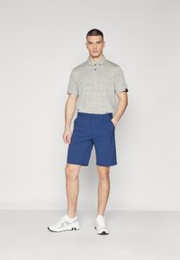 Gray striped polo shirt with a collar, two buttons, paired with blue shorts and white sneakers. Simple design and casual fit.