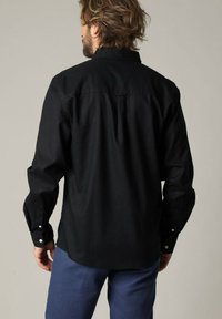 Zwarte lange mouw shirt met een button-down kraag, rugplooidetail en knoopmanchetten, gemaakt van gestructureerde stof.