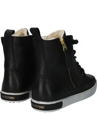 Sneaker alte in pelle nera con interno morbido. Presentano dettagli in zip dorata, lacci neri e suola bianca con accenti testurizzati.