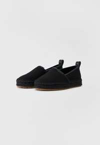 Zapatos espadrilles negros con una parte superior de tela texturizada, un lado elástico y una entresuela trenzada de yute. Suela de goma para mayor agarre.