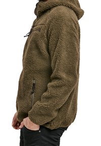 Giacca in pile verde oliva con superficie testurizzata, zip frontale e tasche laterali. Presenta un cappuccio e una vestibilità comoda.