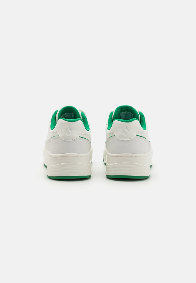 Des baskets blanches avec une finition texturée et des accents verts sur le talon et l'intérieur. Elles présentent une pointe arrondie et un design de semelle plate.