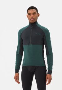 Maillot de cyclisme à manches longues vert et noir avec un col haut, fermeture éclair sur le devant, et détail de logo, fabriqué en tissu léger et texturé.