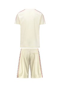 Camicetta crema a maniche corte con strisce laterali rosse, abbinata a pantaloni corti coordinati con accenti rossi e lati a motivo logo. Finitura in tessuto morbido.