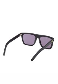 Occhiali da sole neri in plastica con lenti quadrate, di colore viola. Presentano una finitura opaca elegante e un sottile logo verde su un'asta.