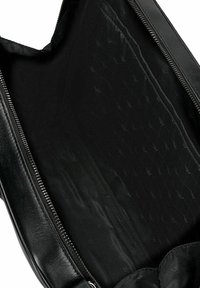 Interno di una borsa in pelle nera con una texture liscia, dotata di chiusura con zip e una discreta fodera a motivo diamante. Design spazioso e privo di decorazioni.