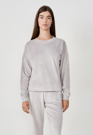 Light gray velour sweatshirt with long sleeves, crew neck, and relaxed fit. Soft texture, minimalist design, paired with matching pants.