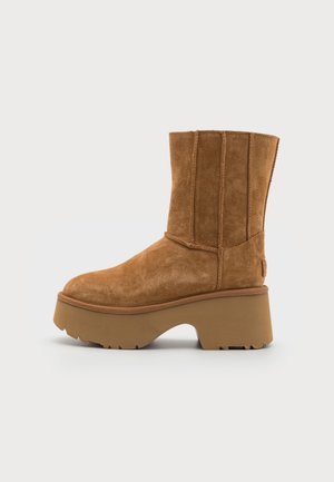 Brune suedes ankelstøvel med en chunky plattformsåle, med vertikale sømmer og rund tå. Teksturert side og robust design.