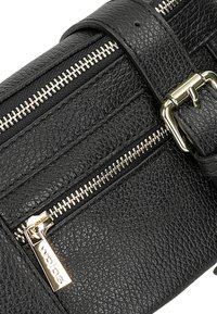 Borsa in pelle nera con materiale testurizzato, zip argento prominenti e un dettaglio in metallo dorato sulla fibbia della tracolla.