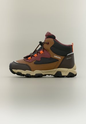 Botte de randonnée marron et noire avec des accents orange, semelle robuste et système de laçage rapide, portant l’étiquette Geox Amphibiox sur le côté.
