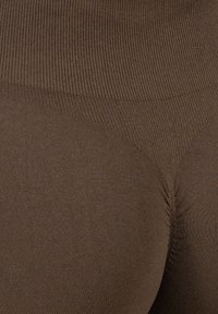 Bruine naadloze leggings met een geribbelde textuur. Heeft een hoge tailleband en een strakke pasvorm, die de gladde contouren benadrukt.
