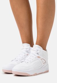 Białe trampki high-top z różowymi akcentami, z górą wykonaną z gładkiej skóry, wyściełanym kołnierzem i perforowanym noskiem dla lepszej wentylacji.