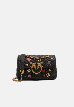 Black quilted leather handbag with gold chain strap, gold bird clasp, and colorful heart, clover, and emblem embellishments on front.