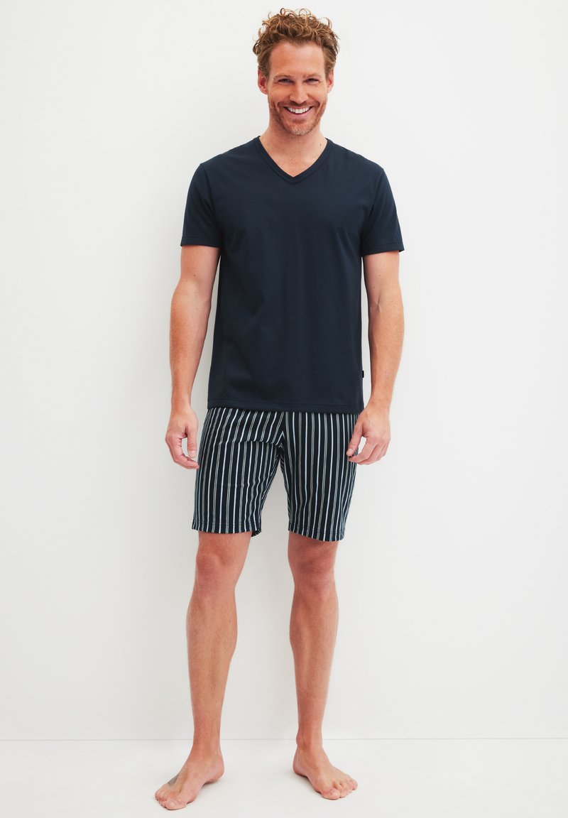 Marineblauw V-hals T-shirt gecombineerd met zwart-witte gestreepte shorts. De stof lijkt soepel, en de shorts hebben een verstelbare tailleband.