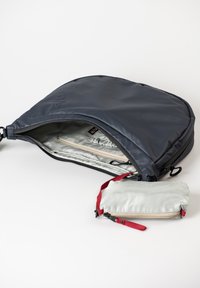 Dunkelblauer Stoff-Rucksack mit weiter Öffnung, ausgestattet mit einem helleren Innenraum und einem kleinen grauen Beutel mit einem roten Reißverschluss-Detail innen.