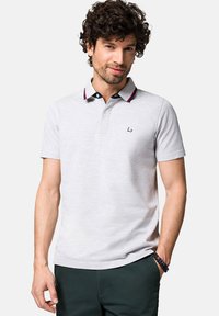 Jasnoszara koszulka polo z dwu guzikowym zapięciem, granatowym kołnierzykiem z czerwonym wykończeniem oraz logo na piersi. Krótkie rękawy w klasycznym kroju.