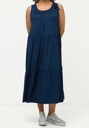 Granatowa sukienka bez rękawów z falbankowym dekoltem i wiązaniem na ramieniu, z warstwowymi, marszczonymi sekcjami.