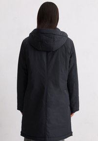 Czarna pikowana kurtka z kapturem, o prostym kroju i detalach szwów. Materiał wydaje się gładki o matowym wykończeniu.