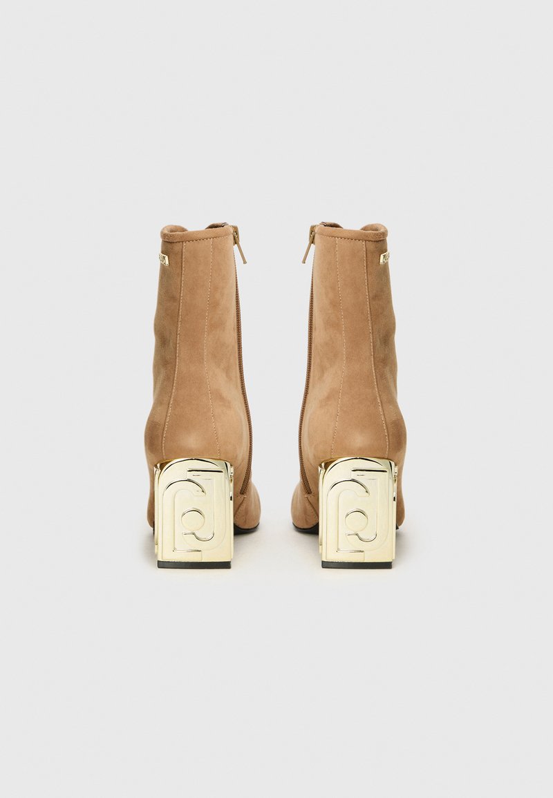 Beige Wildleder Stiefeletten mit goldenen geometrischen Blockabsätzen, ausgestattet mit einem Reißverschluss auf der Rückseite und einer glatten Textur.