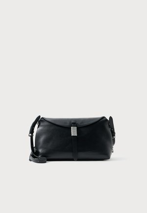 Sac à épaule en cuir noir avec une forme arrondie, doté d'une fermeture à rabat et d'accents en métal. Sangle réglable incluse.