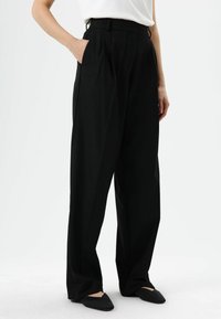 Schwarze Hosen mit weitem Bein aus glattem Stoff, mit vorderen Abnähern, seitlichen Taschen und einem taillierten Bund für eine strukturierte Passform.