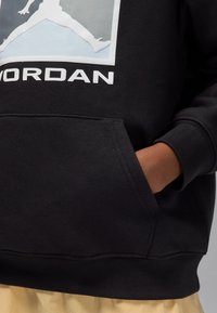 Black hoodie with a front pocket, featuring a white "Jordan" logo and graphic of a leaping figure. Soft fabric with a classic fit.