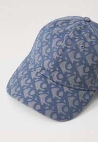 Blue cap with a patterned design featuring light gray graphics. Made of textured fabric, it has a curved brim and breathable eyelets.