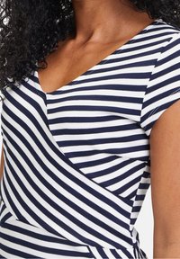 Navy and white striped top with a V-neck and cap sleeves. Features a wrap design with a soft, stretchy cotton material.