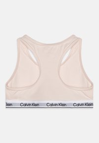 Reggiseno sportivo rosa chiaro con schiena a forma di U, dotato di una banda bianca con il logo nero "Calvin Klein". Realizzato in tessuto morbido e elastico.