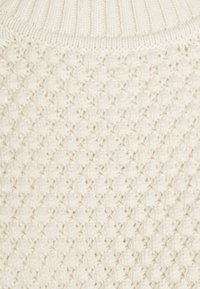 Maglione lavorato a maglia color crema con un motivo a diamante testurizzato e colletto a coste. Filato morbido e spesso con un aspetto accogliente.