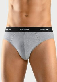 Grijze katoenen slips met een zwarte elastische tailleband waarop het "Bench." logo in het wit staat. Glad textuur en contournontwerp voor een goede pasvorm.
