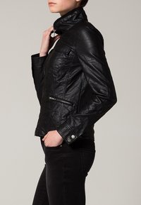 Svart skinnjacka med hög krage, dragkedja framtill och två sidofickor. Har en åtsittande design och slät yta.