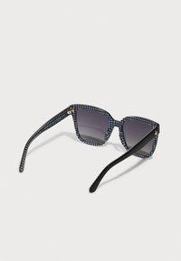 Ochelari de soare cu un cadru întunecat albastru în model houndstooth, brațe negre și lentile gri cu un gradient. Au accente de aur subtile la balamale.