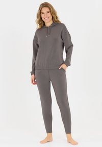 Graues Athleisure-Set mit Kapuzenpulli und Kordelzug sowie elastischen Bündchen, kombiniert mit figurbetonten Leggings. Glattes, leichtes Material.