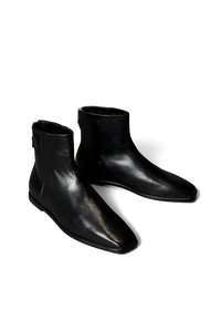 Stivaletti alla caviglia in pelle nera con punta appuntita e design elegante. Presentano cerniere laterali e una texture liscia con dettagli di cuciture sottili.