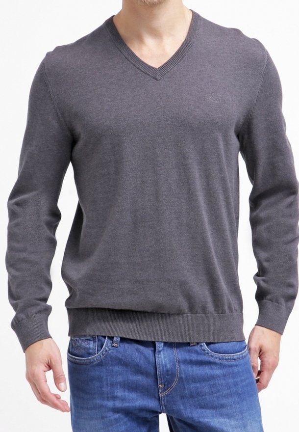 Szary sweter z dekoltem w serek, wykonany z miękkiego dzianinowego materiału, z prążkowanymi mankietami i dołem, noszony na niebieskich dżinsach. Gładka faktura, bez widocznych wzorów.