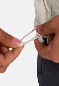 Graue Jacke mit elastischem Kordelzug und verstellbarem Toggle am Bündchen. Nahaufnahme einer Hand, die den Kordelzug anpasst. Glatte Textur, sportliches Design.