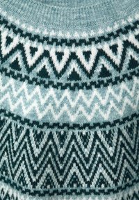 Pull en maille présentant un motif géométrique bleu sarcelle et blanc avec des motifs en zigzag et triangulaires. Texture douce avec un col rond.
